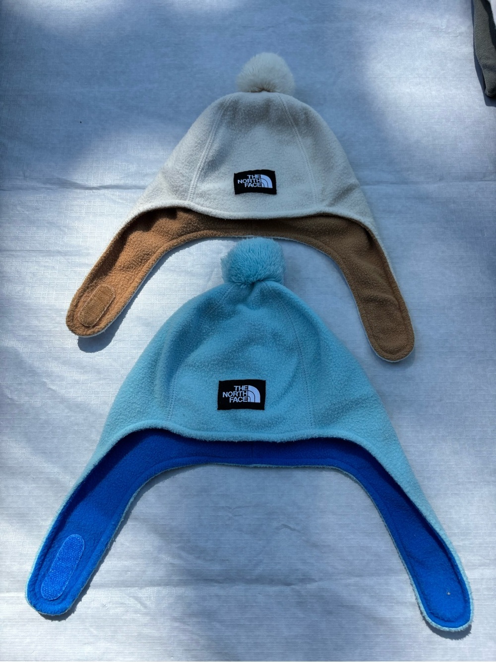 The North Face Fleece Earflap Pom-Pom Hats in Cream & Light Blue